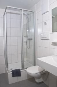 a white toilet sitting in a bathroom next to a shower at Hotel Wanner in Böblingen