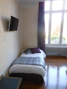 a bedroom with a bed and a tv and a window at Logis - Hôtel Restaurant l'Ecu de France in Malesherbes