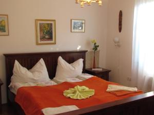 a bedroom with a bed with an orange blanket at Torkolat Panzió in Tokaj