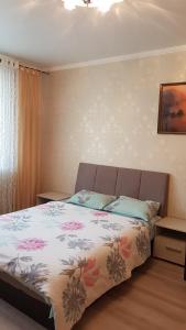 a bedroom with a bed with a floral bedspread at Apartments Avrora, Gagarina 75 in Oryol