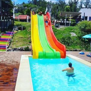 a man in a swimming pool with a rainbow slide at Complejo Laderas del Cerro in Piriápolis