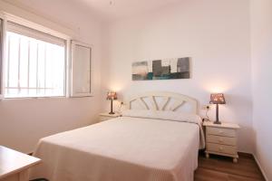 オリーバにあるOLIVA HOLIDAYS 4の白いベッドルーム(白いベッド1台、ランプ2つ付)