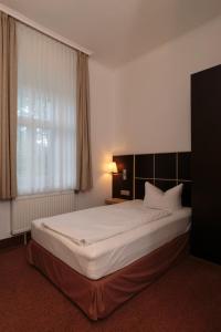 a large bed in a hotel room with a window at Hotel Landhaus Schlachtensee in Berlin