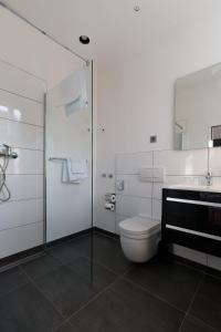 a white bathroom with a toilet and a sink at Hotel Landhaus Schlachtensee in Berlin