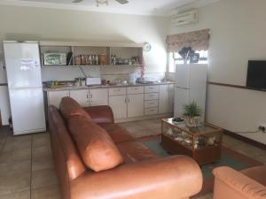 a living room with a brown leather couch and a kitchen at Oewerpalms View in Oudtshoorn
