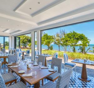 a dining room with tables and chairs and a view of the ocean at Luxury Apartment - Azuri Village - Roches Noires in Roches Noires