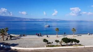 una spiaggia con palme e una barca in acqua di Sant'Agostino Affittacamere a Reggio di Calabria