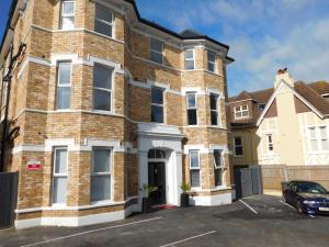 a large brick building with a car parked in a parking lot at Stylish Apartment in Victorian Conversion FREE PARKING & PRIVATE PATIO Close to Beach Town Centre & BIC in Bournemouth