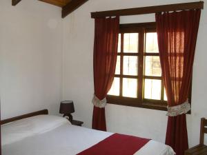 1 dormitorio con 1 cama y una ventana con cortinas rojas en Adi y Dina Cabañas, en La Paloma