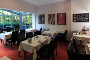 a dining room with tables and chairs and a window at Hotel Landhaus Schlachtensee in Berlin +37 photos
