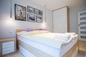 a large white bed in a room with pictures on the wall at Apartament wrzos z ogródkiem in Pogorzelica
