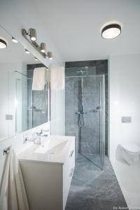 a white bathroom with a sink and a shower at Apartament wrzos z ogródkiem in Pogorzelica