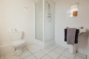 a white bathroom with a toilet and a shower at Dunes Hotel in Whitley Bay