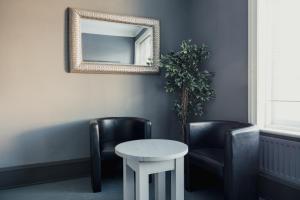a mirror on a wall with two chairs and a table at Dunes Hotel in Whitley Bay