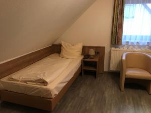 a small bedroom with a bed and a chair at Apartment-Pension Schwalbennest in Herzogenaurach
