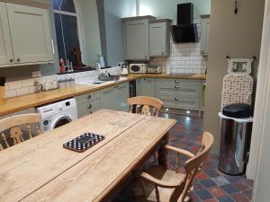 a kitchen with a wooden table and chairs in it at Renovated Church close to the beach in Llanelli