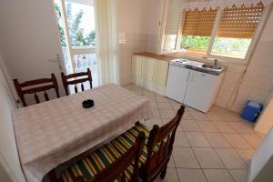 eine Küche mit einem Tisch und einem Tisch und Stühlen in der Unterkunft Apartment Kod Stipe in Vrsi