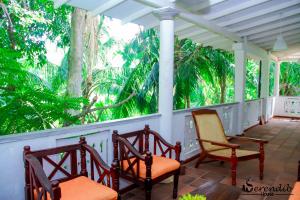 a porch with chairs and trees in the background at Serendib House in Unawatuna