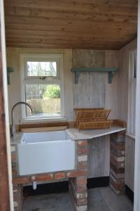 a kitchen with a white sink and a window at Glen Farm Glamping in Cromer