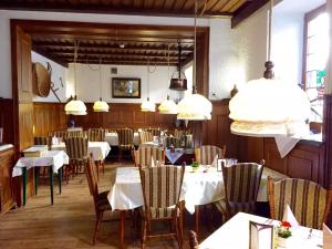 a dining room with tables and chairs and pendant lights at Hotel Weingut Schützen in Senheim