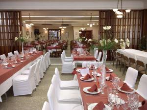 a dining room with long tables and white chairs at Hostal Restaurante El Paso in Bailén
