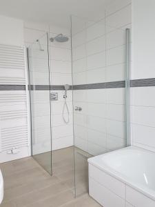 a bathroom with a glass shower with a tub at Ferienhaus Hafenzeit in Cuxhaven +39 photos