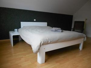 een wit bed in een slaapkamer met een houten vloer bij Chez Paul in Ieper