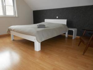 ein weißes Bett in einem Zimmer mit Holzboden in der Unterkunft Chez Paul in Ypern