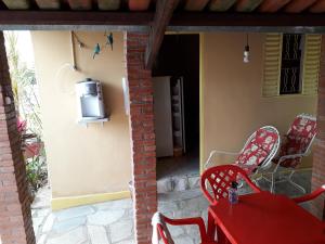 eine Terrasse mit einem roten Tisch und Stühlen sowie einem TV in der Unterkunft Suítes Dona Ilda in Pirenópolis