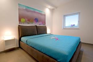 Schlafzimmer mit einem Bett mit blauer Bettwäsche und einem Fenster in der Unterkunft Holiday home M1 & M2 in Pula