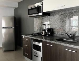 eine Küche mit einem Edelstahlkühlschrank und einer Spüle in der Unterkunft Studio Loft Polanco with POOL in Mexiko-Stadt