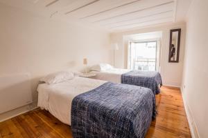 two beds in a white room with wooden floors at Rua Sao Bento Apartment in Lisbon