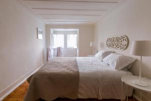 a white bedroom with a large bed and a table at Rua Sao Bento Apartment in Lisbon +13 photos
