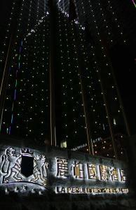 a sign in front of a large building at night at La Perle International Hotel - Free shuttle between hotel and Exhibition Center during Canton Fair & Exhibitor registration Counter in Guangzhou