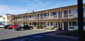 un edificio de apartamentos con coches aparcados en un aparcamiento en Astro Motel, en San Bernardino