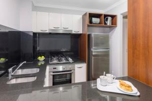 a kitchen with a sink and a stove top oven at Oaks Brisbane Lexicon Suites in Brisbane