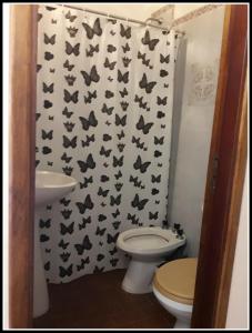 baño con aseo y cortina de ducha con mariposas en Hotel Molise en Villa Gesell