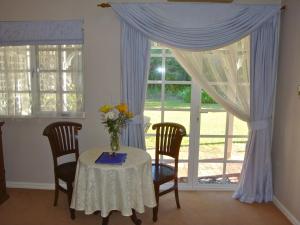 a table with chairs and a vase of flowers on it at Lanterns Retreats in Dunsborough
