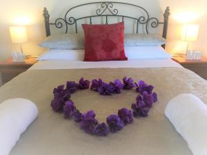 a heart made out of purple flowers on a bed at Balingup Highview Chalets in Balingup