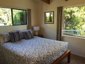 a bedroom with a bed and two large windows at By the Bay Beachfront Apartments in Mangonui