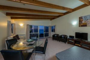 a living room with a glass table and chairs at By the Bay Beachfront Apartments in Mangonui