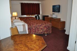 a hotel room with a bed and a television at Golden Lion Motel in Raymond
