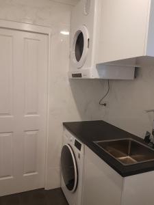 a white kitchen with a sink and a washing machine at Edwin Place Apartment in Glenwood +2 photos