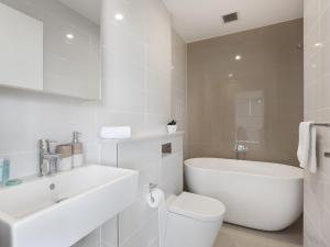 a white bathroom with a toilet and a sink at As the Sun Sets - Modern and Spacious 2BR Zetland Apartment Facing the Setting Sun in Sydney
