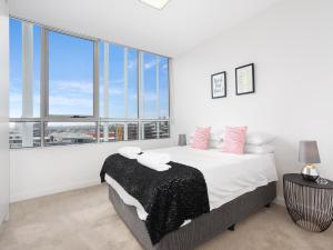 シドニーにあるAs the Sun Sets - Modern and Spacious 2BR Zetland Apartment Facing the Setting Sunの白いベッドルーム(ベッド1台、大きな窓付)