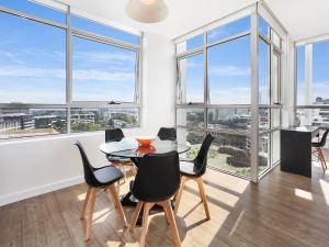 ein Esszimmer mit einem Tisch, Stühlen und Fenstern in der Unterkunft As the Sun Sets - Modern and Spacious 2BR Zetland Apartment Facing the Setting Sun in Sydney