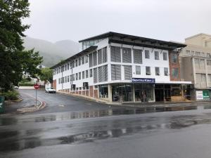 a large white building on a street in the rain at Zeederberg Corner in Paarl