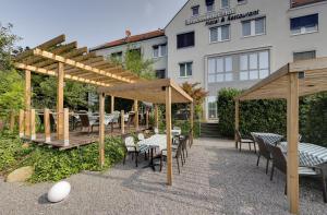 eine Terrasse mit Tischen und Stühlen vor einem Gebäude in der Unterkunft Brackweder Hof in Bielefeld