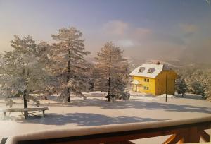 ein gelbes Haus im Schnee mit einem Picknicktisch in der Unterkunft Apartment Oaza Mira in Divčibare