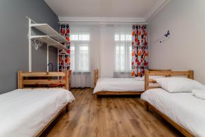 two beds in a room with wooden floors and windows at Orange Cat Rooms in Riga